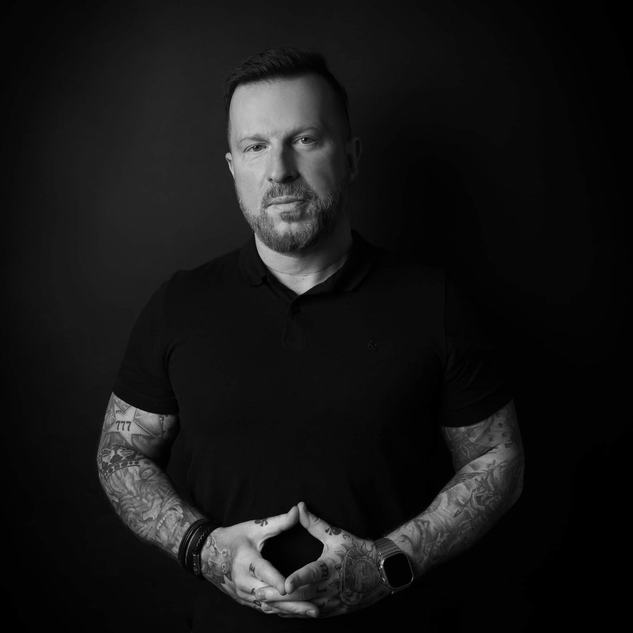 Rafał Bielecki — czarno-biały portret z widocznymi tatuażami na przedramionach